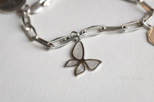 Herinneringssieraad vlinder hangertje van rvs zilver met parelmoer gevuld met as, aan armband.
