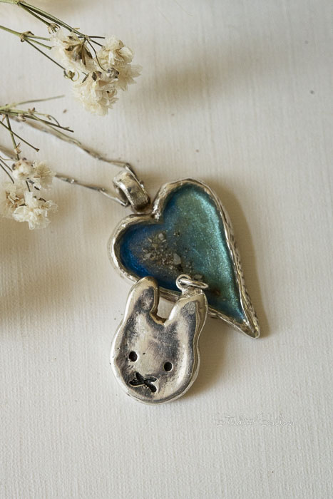 2 handgemaakte puur zilveren ashangers, een hartje met blauw en nijntje.