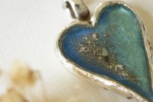 Handgemaakte echt zilveren hanger met blauwe kleur en as erin verwerkt, close-up